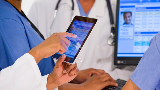 Doctors using digital tablet together in hospital